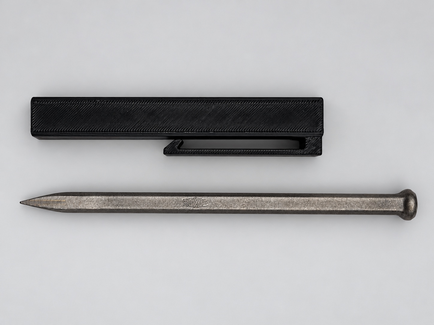 Cleaned photograph of the black chisel holder beside the REXID lettering chisel